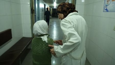 Al Ghouta, Syria - Dr Amani (R) helps a young girl into the hospital. (National Geographic)