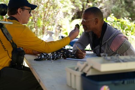 Christian Cooper smells a Hawaiʻi ʻamakihi held by avian technician Bret Nainoa Mossman at the Pu'u Maka'ala Natural Area Reserve. (National Geographic for Disney/Troy Christopher)