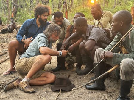 Kerllen Costa, Dr. Steve Boyes, and a group of Angolan tribal hunters check Steve's cellphone video of a ghost elephant at their search camp. (Credit: Ariel Leon Isacovitch)
