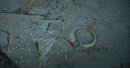 A shark tooth fob, pocket watch and boar tusk bangle in the debris field of the Titanic Digital Twin scan materials. (Credit: Magellan Limited/Atlantic Productions)