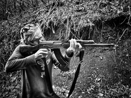 A woman points a rifle in Sinaloa Mountains. (Nick Quested)