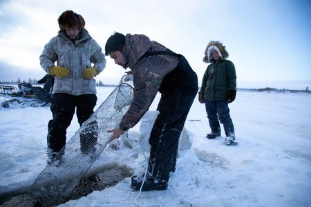 Avery Hoffman lifts their blackfish trap from under neath the ice while his brother, Gage, and mother, Ana, watch. (BBC Studios Reality Productions, LLC/Isaiah Branch - Boyle)