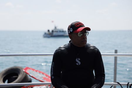 President and CEO of the Tuskegee Airmen National Museum Brian Smith sits on a boat while traveling to the dive site. (National Geographic/Rob Lyall)