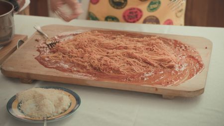 TUCCI IN ITALY - “Le Marche” - Maccheroncini di Campofilone being mixed with a red ragu on a board.  (National Geographic)TUCCI IN ITALY