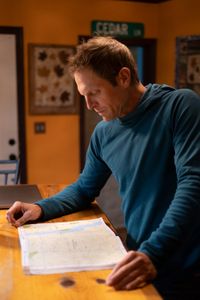 Professional kayaker Ben Stookesberry studies the map of a river on a desktop.  (National Geographic/Harrison Gayton)