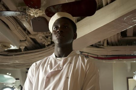 Mess attendant Doris Miller (played by Abdul Sulaiman) is pictured in a WW2 historic reenactment scene for "Erased: WW2's Heroes of Color. The series tells the stories of three Black heroes who miraculously survived the attack on Pearl Harbor. One of these men, mess attendant Doris Miller, defied racial stereotypes when he shot down enemy planes during the attack. (National Geographic/Seye Isikalu)