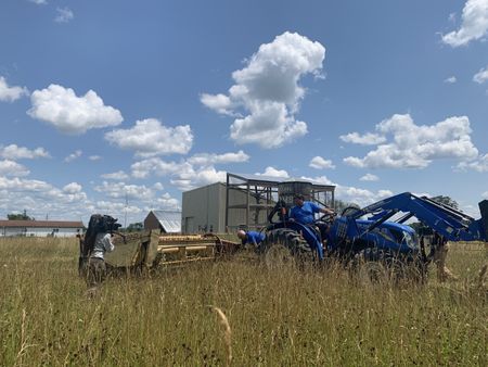 A crew member films Dr. Pol and Charles Pol setting up the tractor to condition the hay at the Pol family's farm. (National Geographic)