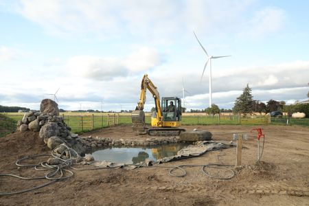 Ben Reinhold operates a mini excavator while working on the Pol family farm's new pond. (National Geographic)