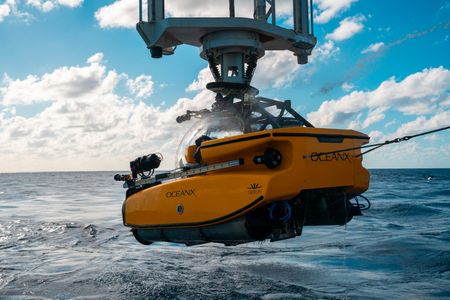 The submarine is lifted out of the water with a crane. (National Geographic/Patrick Hopkins)