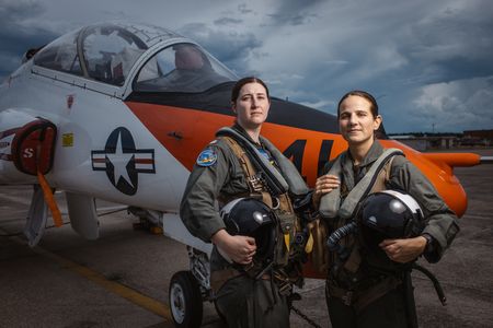 Students LT Carissa Meinster and Captain Steph Harris pose behind a T-45. (Credit: National Geographic/Freddie Claire)