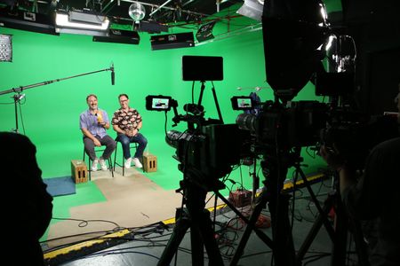 Randy and Jason Sklar holding tropical drinks and laughing surrounded by audio and visual equipment. (National Geographic/Robert Toth)