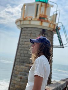 Big wave surfer Justine Dupont stands next to a lighthouse admiring the sea.  (National Geographic/Gene Gallerano)