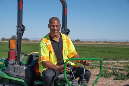 Christian Cooper operates a backhoe to dig a hole for an artificial burrow for the local burrowing owl population in Imperial Valley, CA. (National Geographic/Jon Kroll)