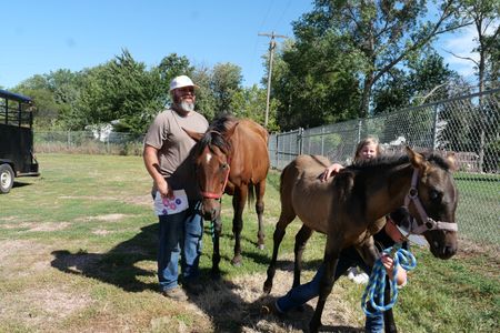 Joey Stansberry watches as his kids Harper, Hadley, and Haivyn try to hold on to their four-month-old foal, Baylor, who is tired of posing for photos. (National Geographic)