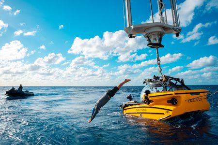 A crew member dives into the water after attaching the sub to the crane. (National Geographic/Patrick Hopkins)
