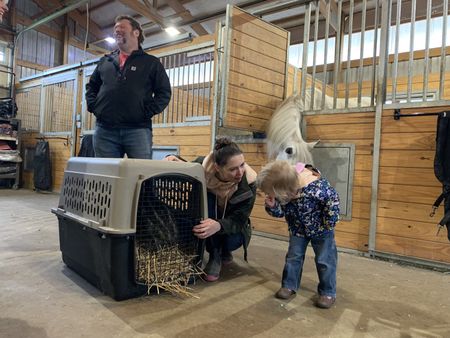 At Yoke Farms, Charles Pol, Beth Pol, and Abigail Pol stand by a carrier with three baby emus, as Abigail inspects the emus. (National Geographic)