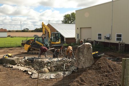 Andrew Hutton, Scott Brady, and Seth Doble lay out the pond liner that will hold the water in the ground for the Pol family farm's new pond while Ben Reinhold oversees them. (National Geographic)