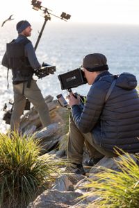 Cameraman Miguel Willis and Researcher Robin Hoskyns filming rockhopper penguins using a steadicam to get on eye level. (National Geographic for Disney/Gerogina Strange)