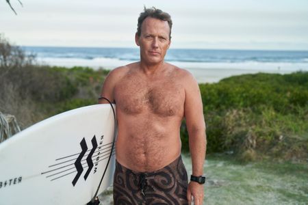 Lee Jonsson with his surfboard at Shelly Beach. (National Geographic/Justine Kerrigan)