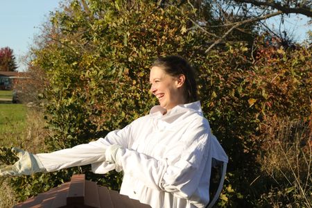 Beth Pol, in a bee suit, smiles while checking on the bees at the Pol family's farm to make sure they are ready for winter. (National Geographic)