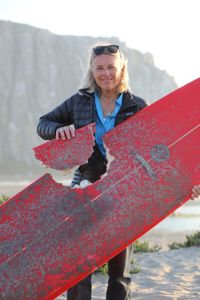 Elinor Dempsey holding up her shark-bitten surfboard. (National Geographic/Mariana Kneppers)