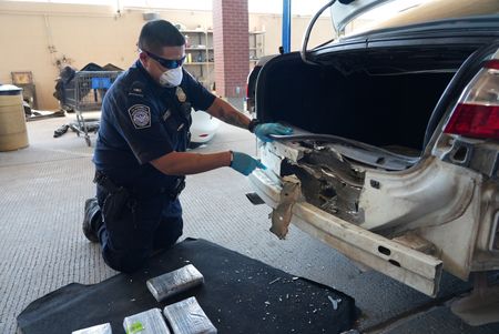 CBP Officer Salcido extracts multiple packages of suspected narcotics discovered smuggled in the rear bumper of a suspect's vehicle in El Paso, Texas. (National Geographic)