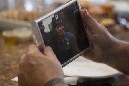 Bill Spade holds a photo of John D'Allara, who was a member of the NYPD Emergency Service Unit and died during the collapse of the North Tower on 9/11. (National Geographic/Virginia Sherwood)
