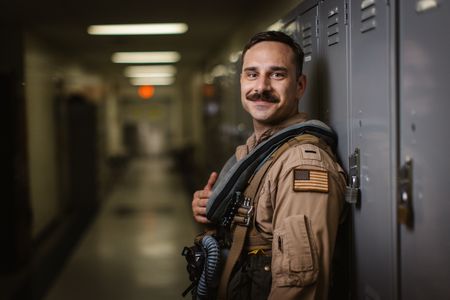 Student LTJG Spenser Neel smiles in the hallway on base. (Credit: National Geographic/Freddie Claire)