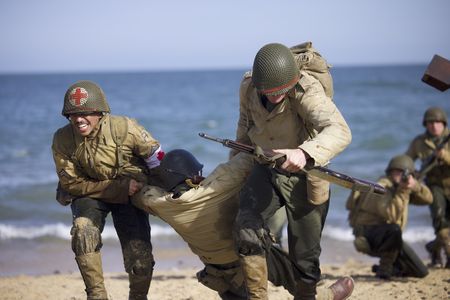 Combat Medic Waverly Woodson Jr., (played by Francesco Di Rauso) helps move the wounded to safety in a scene of a WW2 historic reenactment production for "Erased: WW2's Heroes of Color." Waverly Woodson Jr. was a combat medic who served with the 320th Barrage Balloon Battalion on D-Day. (National Geographic/Rekha Garton)