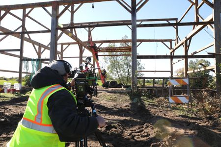 Ben Reinhold stands on a ladder held by Charles Pol as they continue to take down the old barn, while a crew member films them. (National Geographic)