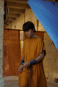 Avianius, played by Frankie Treadaway, sulks on his way home from the Masurius Forge, passing between long drapes of dyed fabric hanging in the streets to dry. (National Geographic/Darrin Zammit Lupi)