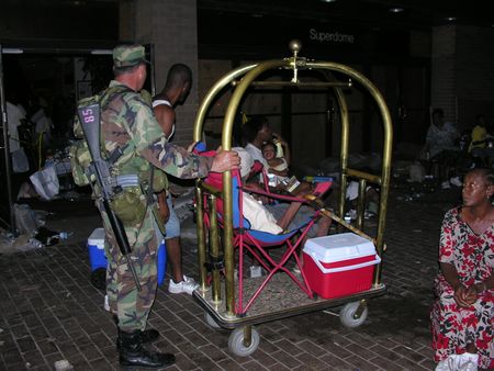 Military members push an elderly in a bellhop cart outside the Superdome after Hurricane Katrina, in New Orleans, La. (Ed Bush)