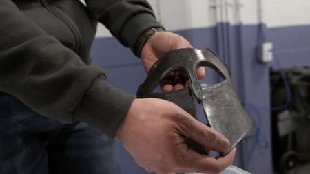 CBP Officer Liu holds a Corinthian helmet after it was discovered in a shipment at the JFK International Airport in New York. (National Geographic)