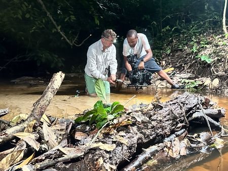 Camera operators Piers Leigh and Clement Kiragu filming in a shallow pool at night time. (National Geographic/Clement Kiragu)