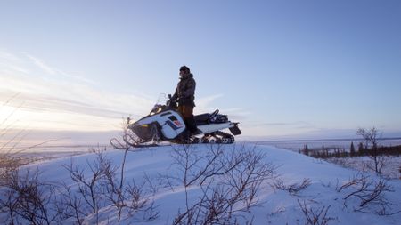 Chip Hailstone spots a herd of caribou passing through the nearby tundra. (BBC Studios/Pedro Delbrey)