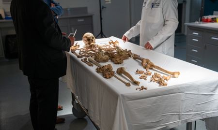 The skeleton of John Doe on a trolley at the Stark County Coroner's Office in 2024. Coroner Ron Rusnak reviews the remains. (National Geographic/Andrew Thompson)
