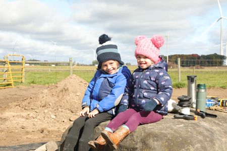 Levi Reinhold and Abigail Pol sit on a large rock by the Pol family farm's new pond. (National Geographic)