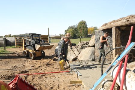 Ben Reinhold rinses off his boots as Seth Doble and Scott Brady level out the wet concrete they are using for the sheep hut's flooring. (National Geographic)