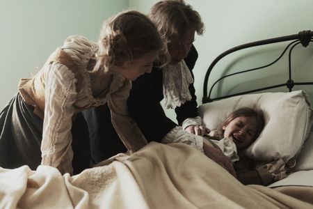 Abigail Williams lays in bed, tortured by an unknown affliction. Samuel Paris watches over her. (Dash Productions Services LTD/Antoan Ivanov)