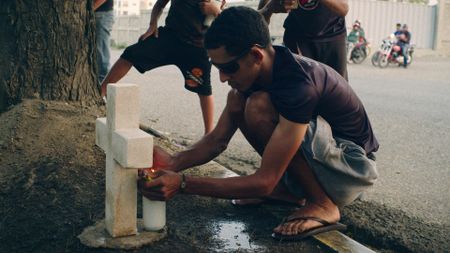 Manolo lights a candle at Chicui's roadside memorial. (National Geographic)