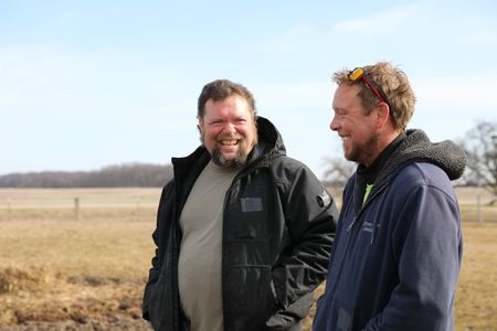 Charles Pol and Ben Reinhold smile as they stand in the Pol family farm's animal pasture, brainstorming a plan to catch the Merino sheep for shearing. (National Geographic)