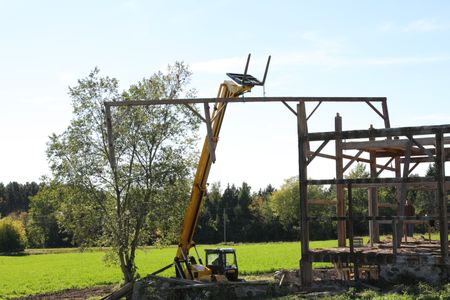 Ben Reinhold operates a telehandler and transports lumber from the old barn around a tree while Bill Klein watches. (National Geographic)