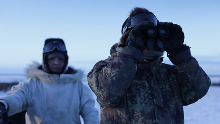 Chip and Agnes Hailstone glass the tundra for a herd of caribou passing through during their migration. (BBC Studios Reality Productions, LLC/Ashton Hurlburt)