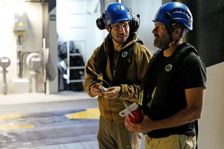 Eric Stackpole and Pedro Afonso stand on the deck of OceanXplorer after a submarine launch at night. (National Geographic/Mario Tadinac)