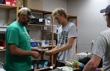 Dr. Ben Schroeder and his son, Chase Schroeder, work together to prepare a splint for Belle, the dog, who is sleeping on the table. Zach Kramer, the owner, watches. (National Geographic)