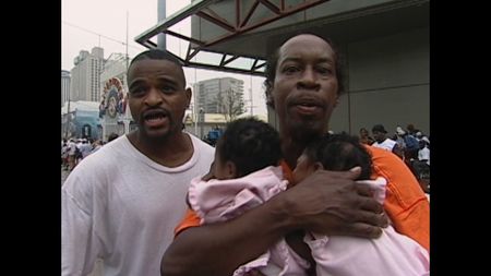 New Orleans resident Kevin Goodman holds his two baby nieces while seeking help from reporters in the face of the dare conditions at the Convention Center after Hurricane Katrina in 2005. (ABC News)