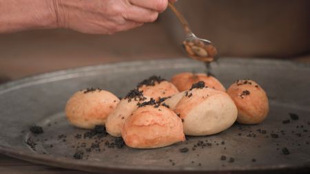 Uli Ties adds toasted poppies to her dish of canci checi, a Ladin staple consisting of fried ravioli, in the outdoor space of her restaurant Plazores.  (credit: National Geographic)