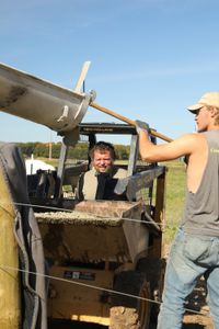 Charles Pol operates the compact track loader as Seth Doble scrapes more wet concrete into the track loader's bucket. (National Geographic)