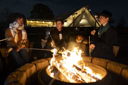 Antoni Porowski makes s'mores around a campfire with other visitors of Collective Retreats on Governor's Island. (National Geographic/Jose Alvarado Jr.)