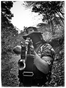 A masked narco points a gun at the camera. (Nick Quested)